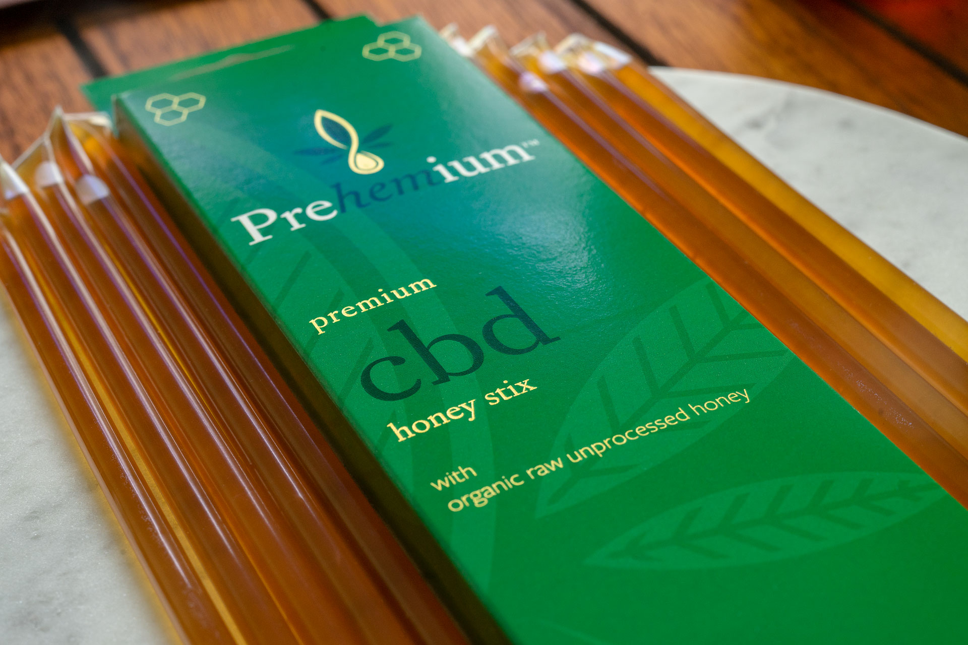 Closeup of Prehemium Premium Honey Sticks 15mg on a white marble slap with 10 sticks divided on either side of the packaging.
